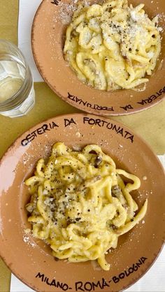 two brown plates filled with pasta on top of a table