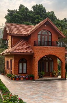 a large brick house with lots of windows and plants in the front yard, surrounded by greenery