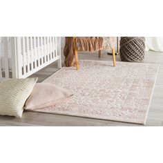 a white rug with pink and beige accents on the floor next to a crib