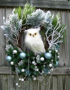 an owl is sitting in the middle of a wreath with christmas decorations on it's front door