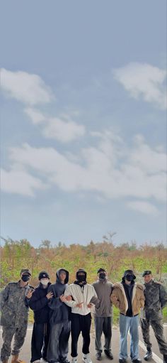 a group of people standing next to each other in front of a sky with clouds