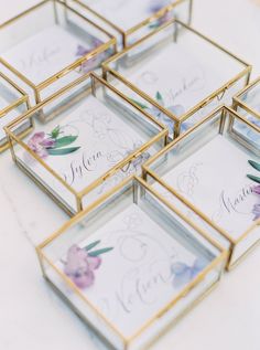 four glass boxes with flowers on them sitting on a table