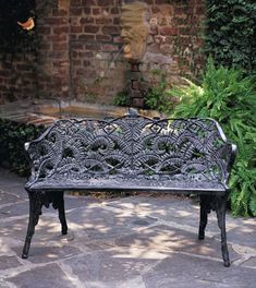 an iron bench sitting on top of a stone patio