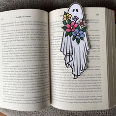 an open book with a ghost and flowers on it