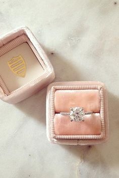 two pink velvet boxes with an engagement ring inside one box and the other is empty