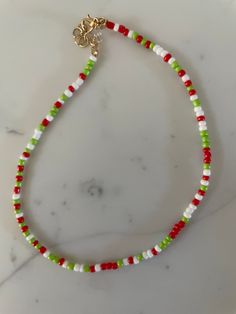 a red, white and green beaded necklace on a marble surface