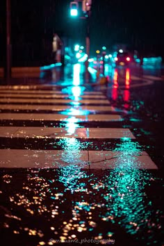 a wet street at night with traffic lights and raindrops on the ground in the foreground