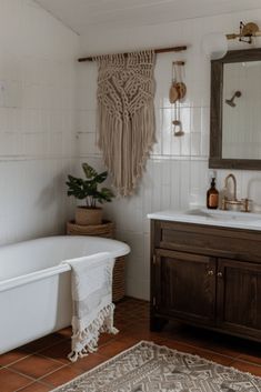 a white bath tub sitting next to a sink under a bathroom mirror on top of a wooden cabinet