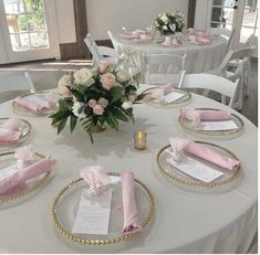 the table is set with pink napkins and place settings for guests to sit at