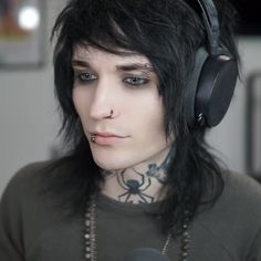 a young man with black hair wearing headphones and piercing on his nose is looking at the camera