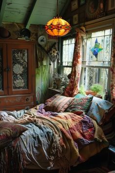 a bed sitting in a bedroom next to a window covered in blankets and throw pillows