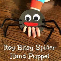 a hand holding a paper spider on top of a wooden table with the words, it'sy bitsy spider hand puppet