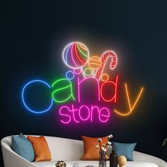 a neon sign that says candy store on the side of a wall next to a couch