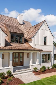 a white house with brown shingles on the roof