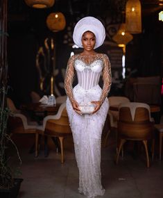 a woman in a white dress and headdress posing for the camera with her hands on her hips