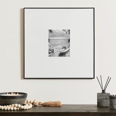 a black and white photo hangs on the wall above a table with candles, vases and other items