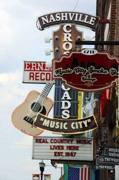 a sign for a music city with an acoustic guitar hanging from it's side