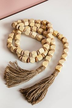 two wooden beads with tassels are sitting on a white surface next to a pink wall