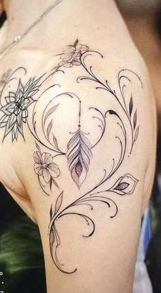 the back of a woman's shoulder with flowers and leaves tattoo on her left arm