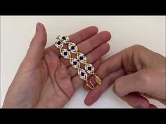 two hands holding a gold and blue bracelet