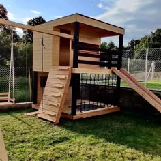 a wooden play structure with a slide in the grass