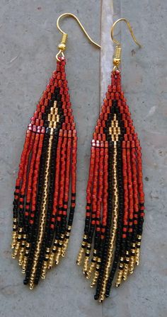 red, black and gold beaded earrings on a marble surface with a white background