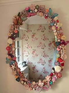 a mirror that has flowers on it and butterflies all over the frame, along with other things