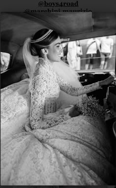 a woman sitting in the back of a car wearing a wedding dress and tiara