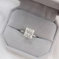 an engagement ring with a princess cut diamond in it's box on a white background