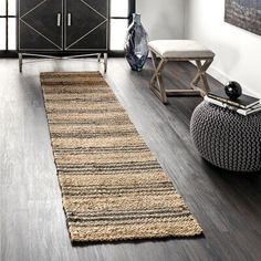 a living room with wood flooring and white walls in the background is a large rug that has been placed on top of it