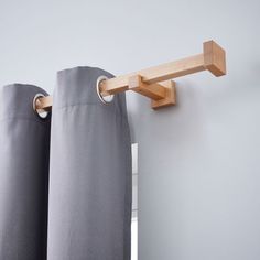 the curtain rod is made from wood and has two rings on each end, which are attached