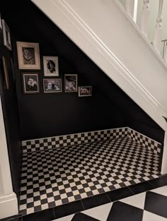 a black and white checkered floor with pictures on the wall in an upstairs stairwell