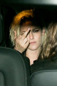 a woman sitting in the back seat of a car holding her hand to her face