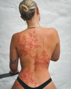 the back of a woman's body with red flowers on it