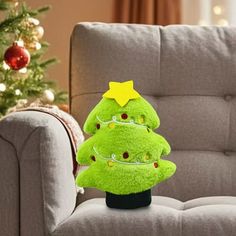 a green christmas tree sitting on top of a black stand in front of a couch