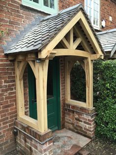 a wooden gazebo sitting in front of a brick building next to a green door