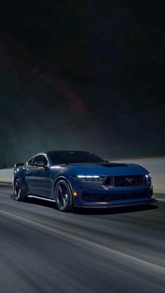 a blue sports car driving down the road at night