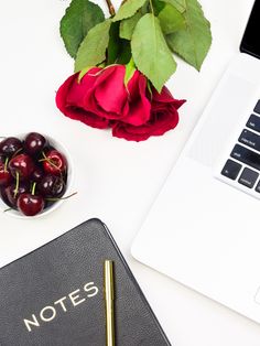 a notebook with the word notes on it next to a bowl of cherries and a rose