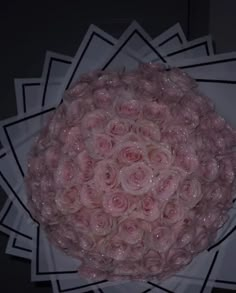 a bouquet of pink roses sitting on top of a white paper plate in front of a black wall