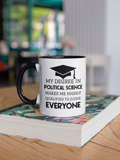 a black and white coffee mug sitting on top of a table next to a book