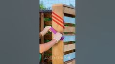 a person is using a sandpaper roller to paint a wooden fence with red and white stripes