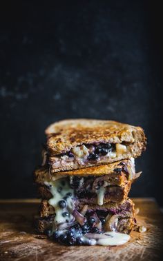 two grilled cheese sandwiches stacked on top of each other with blueberries and onions