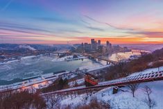 an aerial view of a city and river at sunset, with snow on the ground