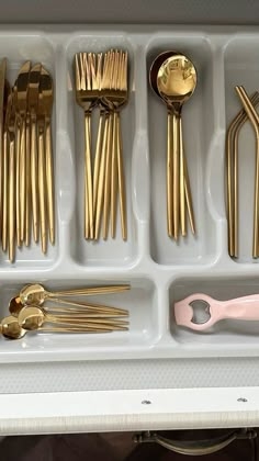 a drawer filled with lots of gold colored utensils and spoons on top of each other