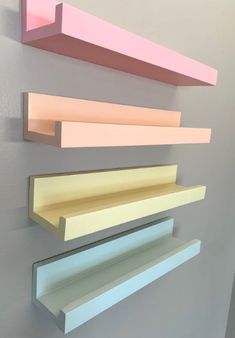 three different colored shelves are hanging on the wall