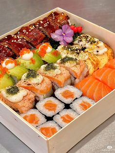 a box filled with different types of sushi and other food on top of a table