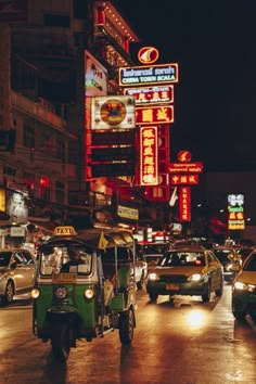 a busy city street at night with cars and neon signs on the side of buildings