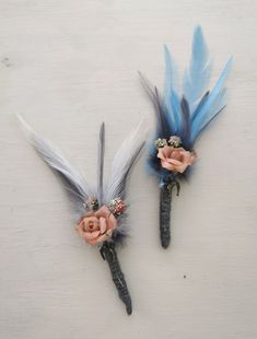 two flowers and feathers are placed on top of each other in the shape of hair clips