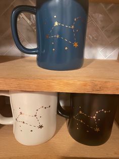 two coffee mugs are sitting on top of each other in a shelf with stars painted on them