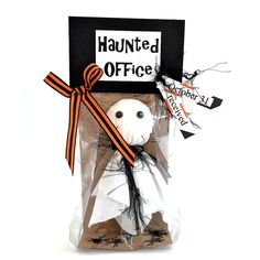 a stuffed ghost in a package with a black and orange ribbon